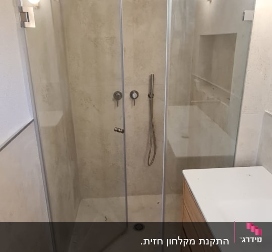 מקלחון זכוכית עם ראש מקלחת וכיור בצד